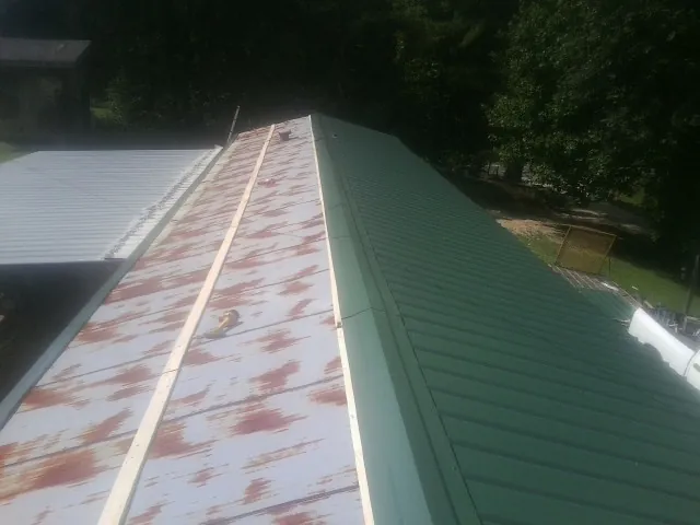 Old rusted panels beside newly installed green metal roofing — Wind Damage Roof Repair by Roofing Brothers in Gatesville