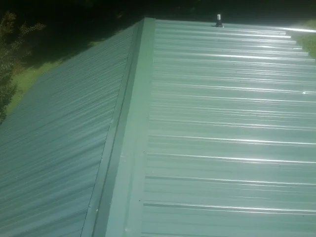 New green metal panels meeting at the ridge of a roof — Flat Roof Repair work by our crew in Gatesville
